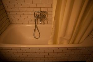 a bath tub with a shower head in a bathroom at Kex Hostel in Reykjavík