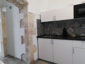 a kitchen with white cabinets and a sink at Triskelion in Scicli