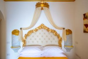 a white bed with a gold headboard with curtains at Palazzo Rocco Villa Sunshining in Love in Praiano