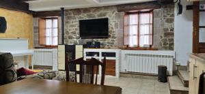 Casa Martiko في Eugi: غرفة معيشة مع تلفزيون على جدار حجري