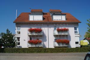 ein weißes Gebäude mit roten Blumen auf den Balkonen in der Unterkunft Weingut Landmann Ferienwohnungen in Freiburg im Breisgau