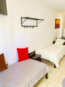 two beds in a room with a red pillow on it at Batistas Apartments in Naousa