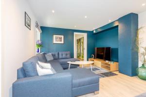a blue living room with a couch and a tv at Modern Apartment with panorama wiew in Blakset