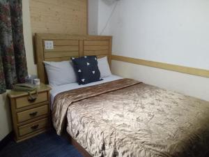 a bedroom with a bed and a nightstand with a bed sidx sidx at 鑽石大旅社 in Pingtung City