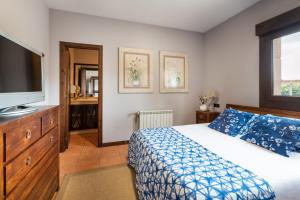 a bedroom with a bed and a flat screen tv at Casa A Pedriña in Amés +19 photos