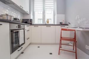 una cocina con armarios blancos y una silla roja. en CR Apartament w Śródmieściu Sienkiewicza 1, en Białystok