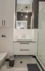 ein weißes Bad mit einem Waschbecken und einer Dusche in der Unterkunft CR Apartament w Śródmieściu Sienkiewicza 1 in Białystok