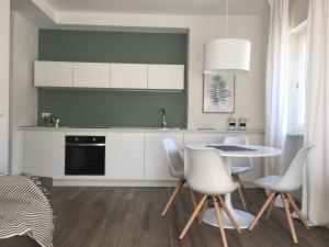 uma cozinha com armários brancos e uma mesa e cadeiras em Casa Daria em Comano Terme