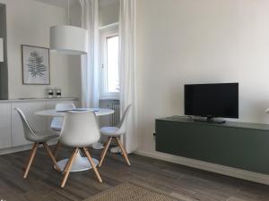 uma sala de estar com uma mesa e cadeiras e uma televisão em Casa Daria em Comano Terme