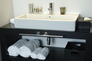 ein Badezimmer mit einem Waschbecken und einem Regal mit Handtüchern in der Unterkunft YOOMA Urban Lodge in Brüssel