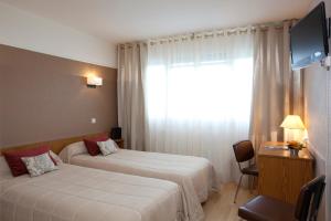 a hotel room with two beds and a television at Brun in Saint-Lattier