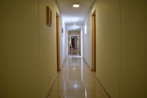 pasillo largo con paredes blancas y suelo de baldosa en Hotel Acuario en Churín