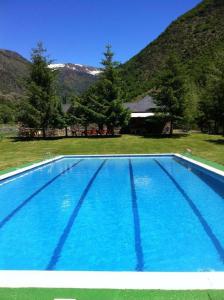 una gran piscina azul frente a una montaña en Apartaments Vall Ferrera, en Àreu