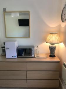a microwave and a lamp sitting on a dresser at Garden Room in Wallingford
