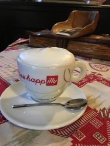 una tazza di caffè su un piatto con un cucchiaio di Agriturismo Randis a Piano dʼArta