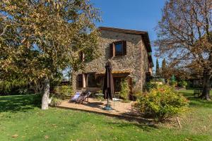 une maison en pierre avec une terrasse et un parasol dans l'établissement Fontanaro Farm and Culinary School, à Paciano