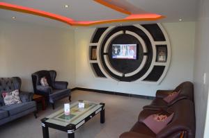 - un salon avec des canapés et une télévision murale dans l'établissement Comfort Hotel Entebbe, à Lyamutundwe