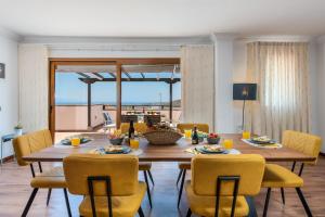 una sala da pranzo con tavolo in legno e sedie gialle di 2 CHARMING VILLA Private Pool and Sea View ad Adeje