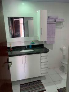 a bathroom with a sink and a mirror and a toilet at Loft Prainha em Arraial Do Cabo in Arraial do Cabo