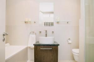 a white bathroom with a sink and a toilet at Eden on the bay 217A-Penthouse in Cape Town
