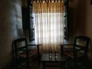 two chairs and a table in a room with a window at La Casona De La Esmeralda in Mascota