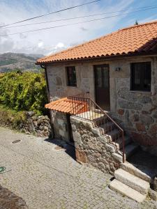 une maison en pierre avec un toit rouge et des escaliers dans l'établissement Casinha do João no Gerês, à Alamela