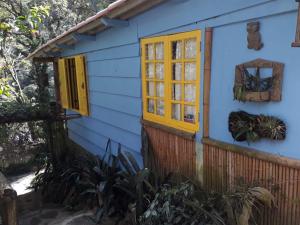 uma casa azul com janelas amarelas e uma cerca em Chales Bamboo Jungle em Petrópolis
