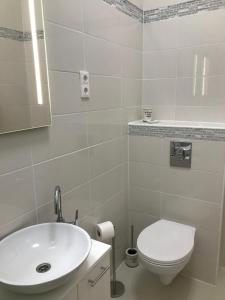 Baño blanco con lavabo y aseo en Bervia Apartman en Szombathely