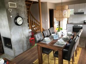 Una mesa de comedor con sillas negras y un reloj. en Villa Manatt, en Stará Lesná