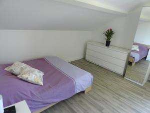 1 dormitorio con cama morada y mesita de noche en Les violettes du Bugey, en Marchamp