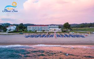 a beach with chairs and a hotel in the background at Blue Sea Hotel in Kanali