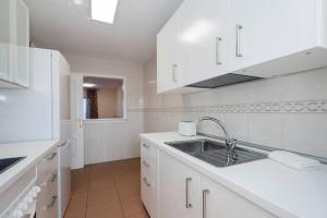 Una cocina con gabinetes blancos y un fregadero. en Family apartment, en Adeje