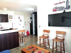 cocina con 2 sillas, mesa y TV en ChileRuca Departamentos Amoblados, en Santiago