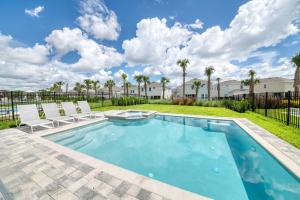 einen Pool mit 2 Stühlen und einen Garten mit Palmen in der Unterkunft Modern Home by Rentyl with Private Pool, Water Park and Resort Amenities - 301B in Orlando