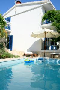 - une piscine en face d'un bâtiment avec un parasol dans l'établissement Apartments MEDITERRANEO, à Kaprije