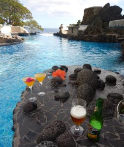 una mesa con copas de bebidas y una piscina en Rockwater Resort, en Tanna Island