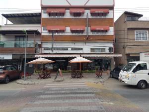 ein Gebäude mit Tischen und Sonnenschirmen auf einer Straße in der Unterkunft Psiu Lanches e Hotel Veraneio in Posse