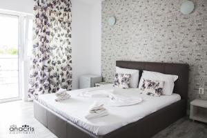 Anacris Guesthouse في كوستينيشت: غرفة نوم بسرير ذو شراشف ووسائد بيضاء