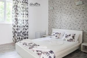 um quarto com uma cama branca com almofadas em Anacris Guesthouse em Costinesti