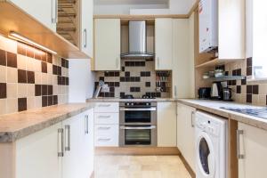a kitchen with white cabinets and a washer and dryer at SunnyBank in Denby Dale