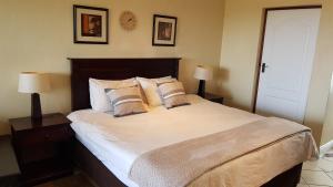 een slaapkamer met een groot bed en 2 lampen op tafels bij Ocean View Villas A08 in Port Edward