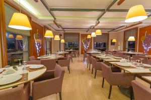 a restaurant with long tables and chairs and yellow lights at Villa Estet Bağ Hotel in Kula