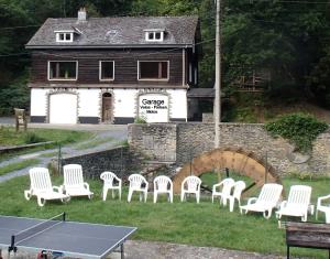 a ping pong table and chairs in front of a building at Le Moulin Lemaire in Houffalize