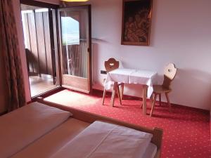 テルメーノにあるGarni Runggner Traubenhofのベッドルーム1室(テーブル、椅子、テーブル付)、窓のある部屋1室が備わります。