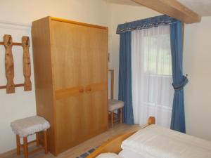 a bedroom with a wooden cabinet and a bed and a window at Haus Waldruh in Niederau