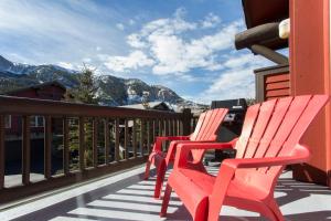 two red chairs sitting on a balcony with mountains at Mammoth Golf Properties By 101 Great Escapes in Mammoth Lakes