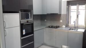 La cuisine est équipée de placards blancs et d'un réfrigérateur noir. dans l'établissement CASA DO SANTO, à Lobios