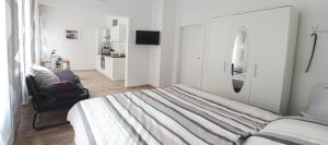 a white bedroom with a bed and a chair at H-Apartment 1 in Triberg