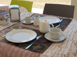 a table with plates and cups and a cell phone on it at B&B L'EDEN DI CAPO BIANCO in Montallegro