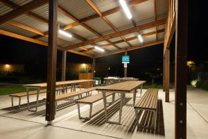 a group of picnic tables and benches under a pavilion at Seaside Holiday Resort in Fingal Bay